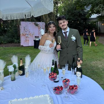 Newlywed couple posing with champagne at outdoor wedding.