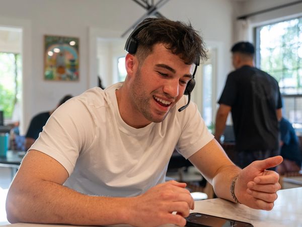 A man on white shirt on headphones using a smart phone