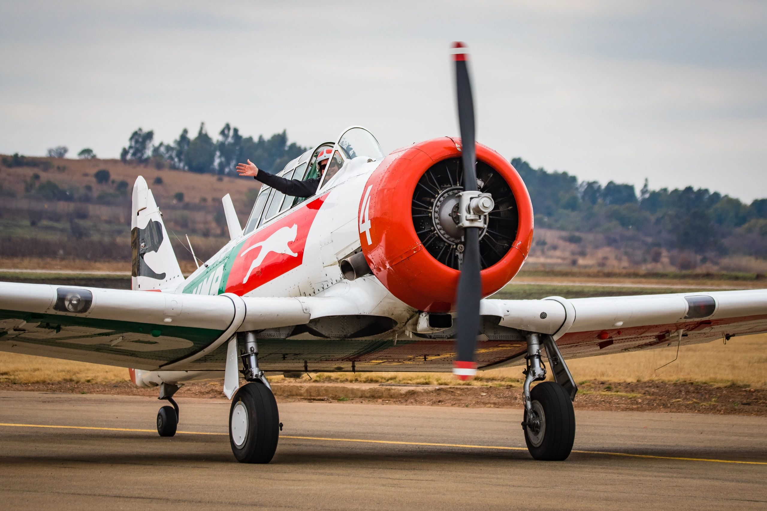 pilot waving his hand from a small aircraft