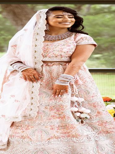 Bride in a beautifully embroidered pink traditional outfit with henna and jewelry.