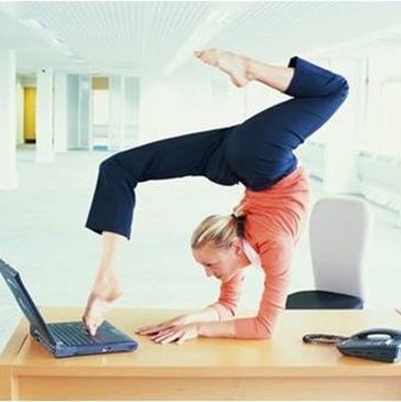 Blonde woman doing a backbend yoga pose with toes on laptop keyboard,