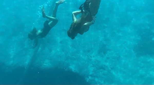 Two people swimming underwater in clear blue ocean.