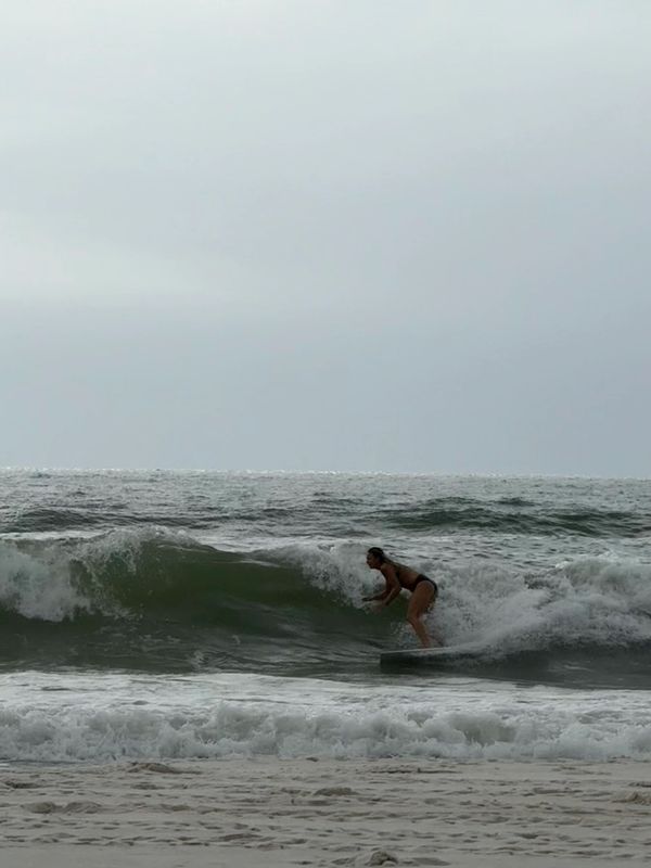 A person surfing on a wave in the ocean near the shore.