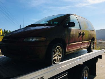 Broken-down minivan being towed away for junk removal service