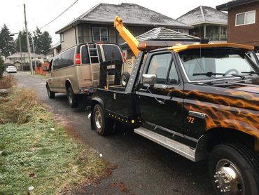 Tow truck towing a junk car from a Burnaby back alley