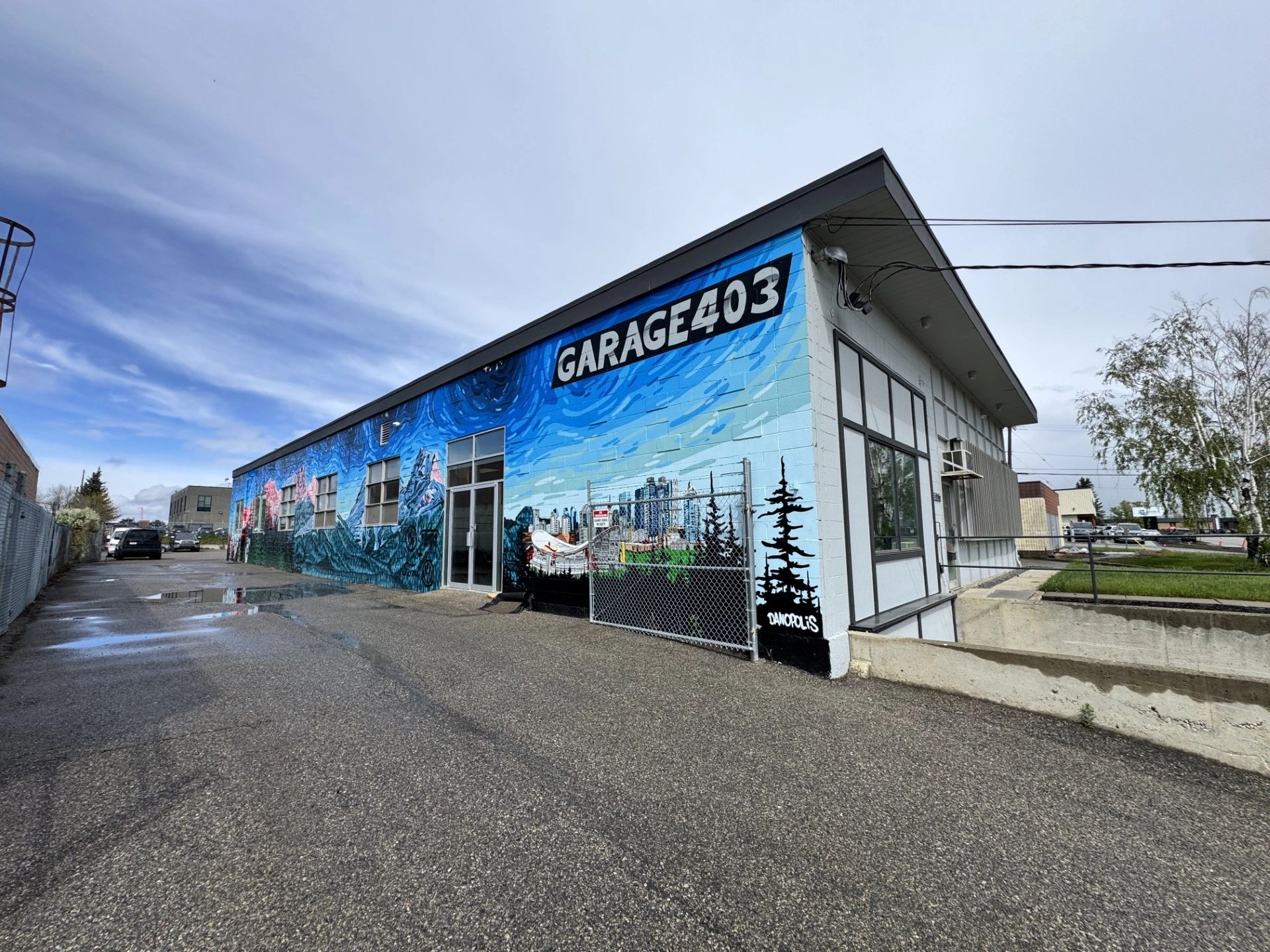 Colorful mural on the exterior wall of Garage 403 under a partly cloudy sky.