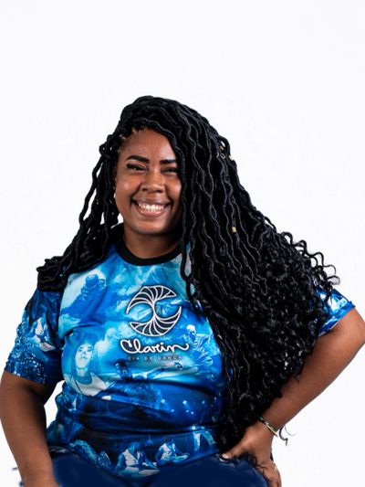Smiling woman with long braided hair in a vibrant blue shirt.