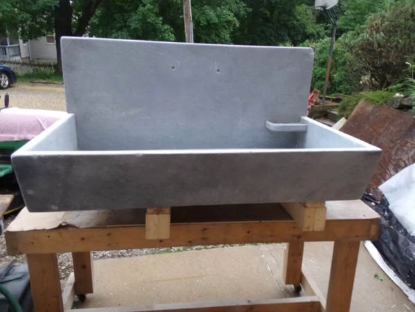 A 36" soapstone slant front sink with backsplash, soap dish and brass drain.