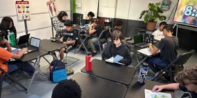 Students engaged in classroom learning with books and tablets.