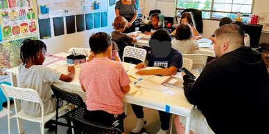 Children working on schoolwork at a classroom table.