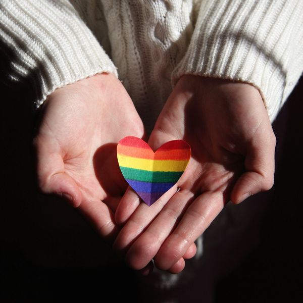 A person holding a rainbow paper heart in hands