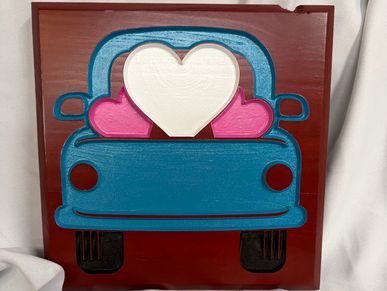 Wooden artwork of a blue car with three heart shapes inside it.