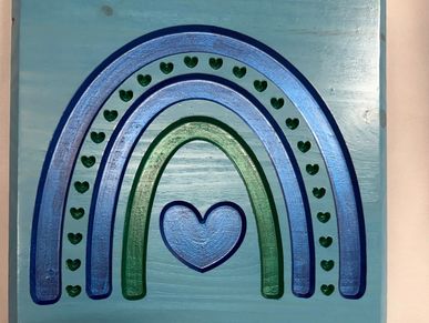 Blue and green rainbow with heart shapes on a wooden board.
