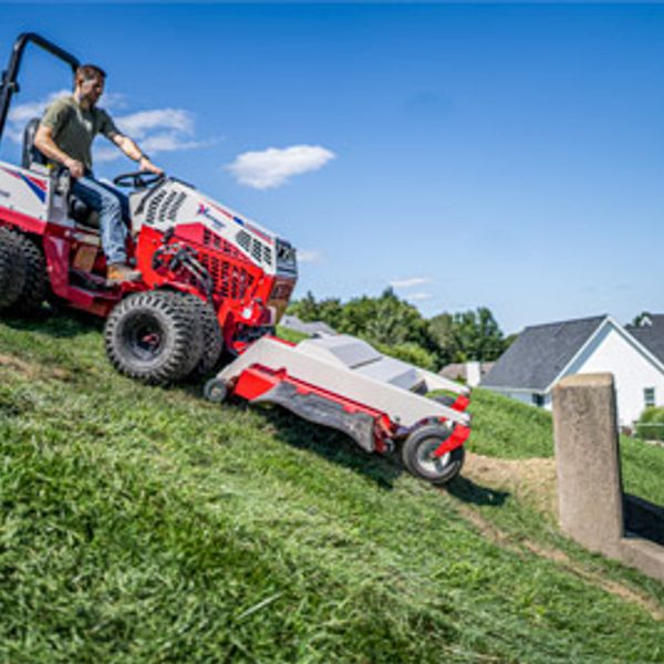 Man mowing a steep grassy hill with a red lawn mower.