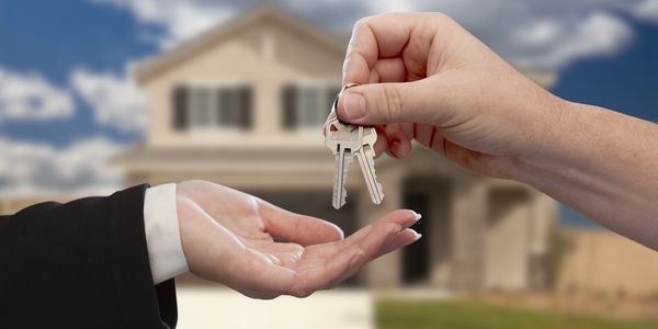 Handing over house keys in front of a new home.