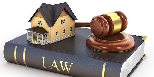 A law book with a miniature house and gavel on top.