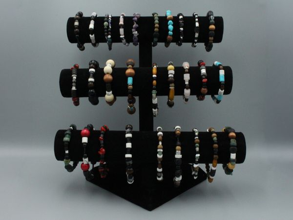 Display of various beaded bracelets on a black stand.