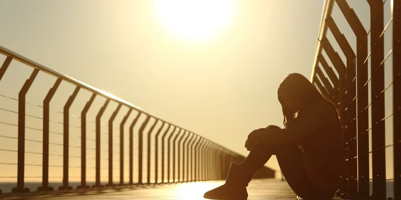 Person sitting alone on boardwalk at sunset — depression therapy for adults in Florida.