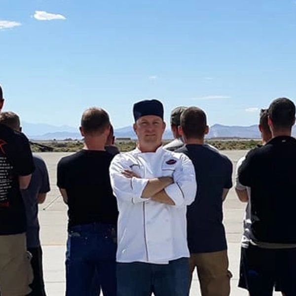 Chef Eric in white chef coat with Huckleberry Grill berry logo.