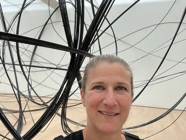 Woman taking a selfie in front of a large black wire sculpture.
