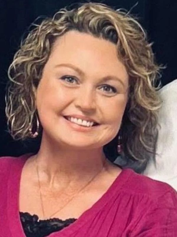 Smiling woman with curly hair in a magenta top.