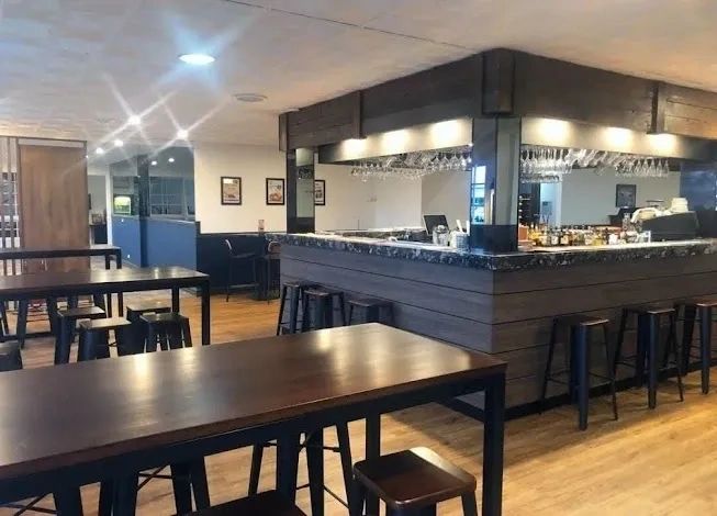 Modern bar area with wooden tables and stools in a cozy setting.