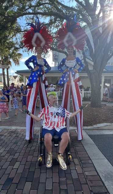 Randy with a stilt walker on each side of him dressed in red, white and blue for Fourth of July.