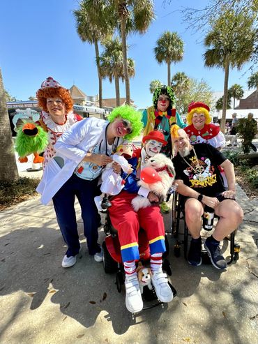 Randy with a yellow mohawk is surrounded by people dressed as clowns.