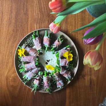 an appetizer plate with asparagus and prosciutto and edible flowers