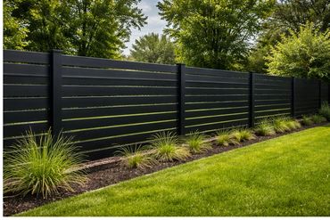 Modern black horizontal slat fence with neatly trimmed grass and plants.
