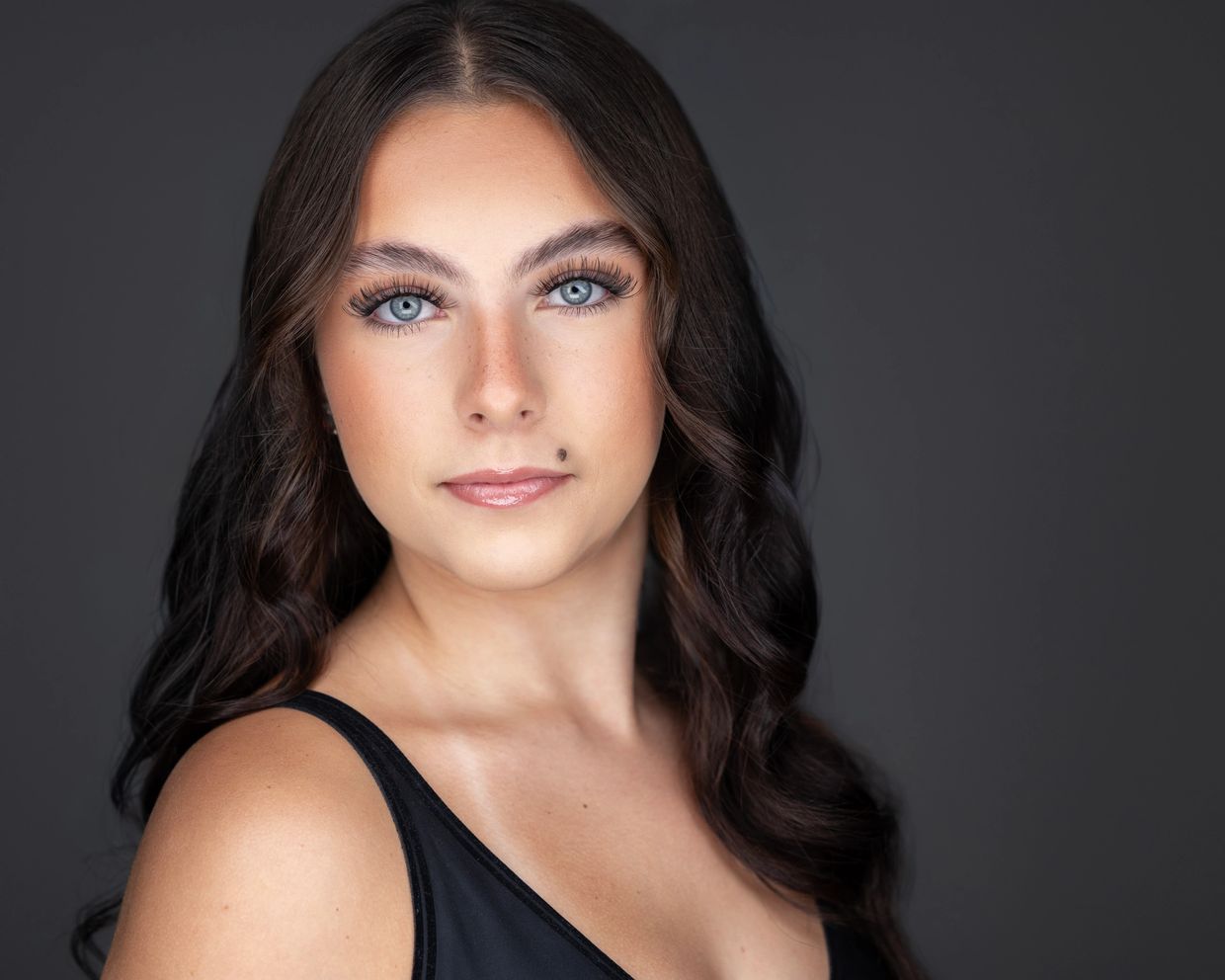 Close-up portrait of a young woman with blue eyes and wavy brown hair.