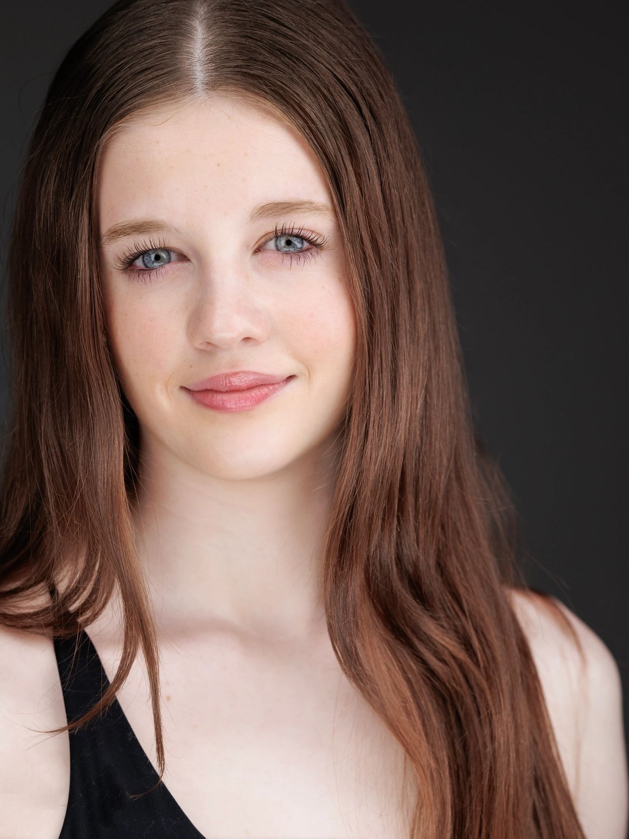Portrait of a young woman with long brown hair and blue eyes smiling gently.