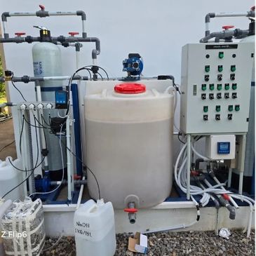 Industrial water treatment setup with tanks, pipes, and control panel outdoors.