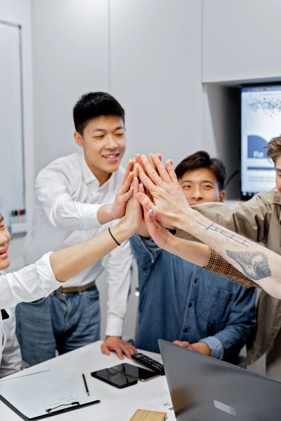 Team celebrating with a group high-five at work.