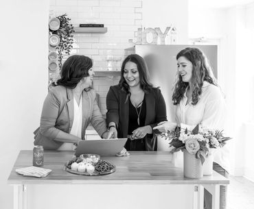 Wedding planner and her team reviewing details on a laptop on a counter in a kitchen.