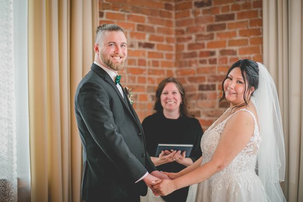 Newlyweds pose for photos with officiant in an industrial setting