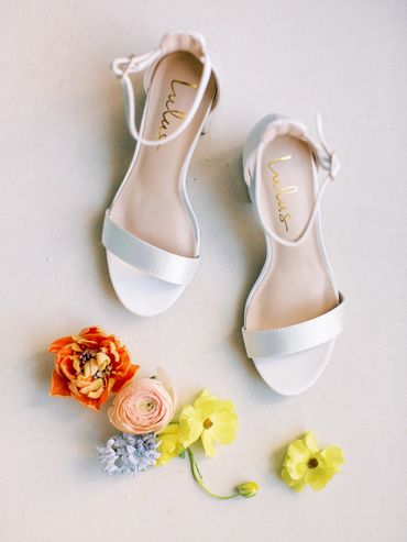 White wedding shoes and floras in peach, light pink, light blue and light yellow.