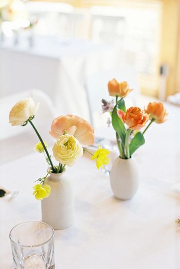 White vases with yellow and peach flowers.