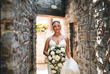 Bride heading down a limestone ally with a large white bouquet.