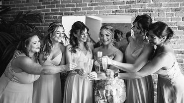 Five bridesmaids and a bride doing a cheers.