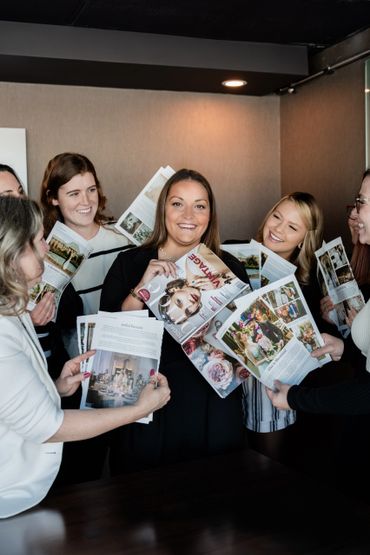 Live mood board with everyone holding up wedding ideas for the bride to be who is in the middle.
