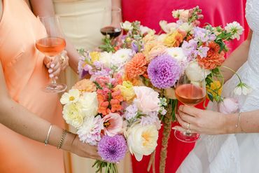 Bridesmaids dressed in pink, peach and light yellow holding colourful summer bouquets.