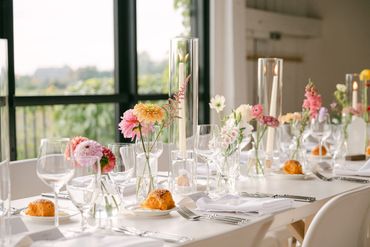 Summer flowers in bud vases and tall taper candles set up down the middle of harvest tables.