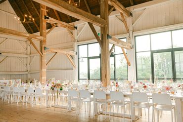 Harvest tables set up inside a white washed rustic barn.