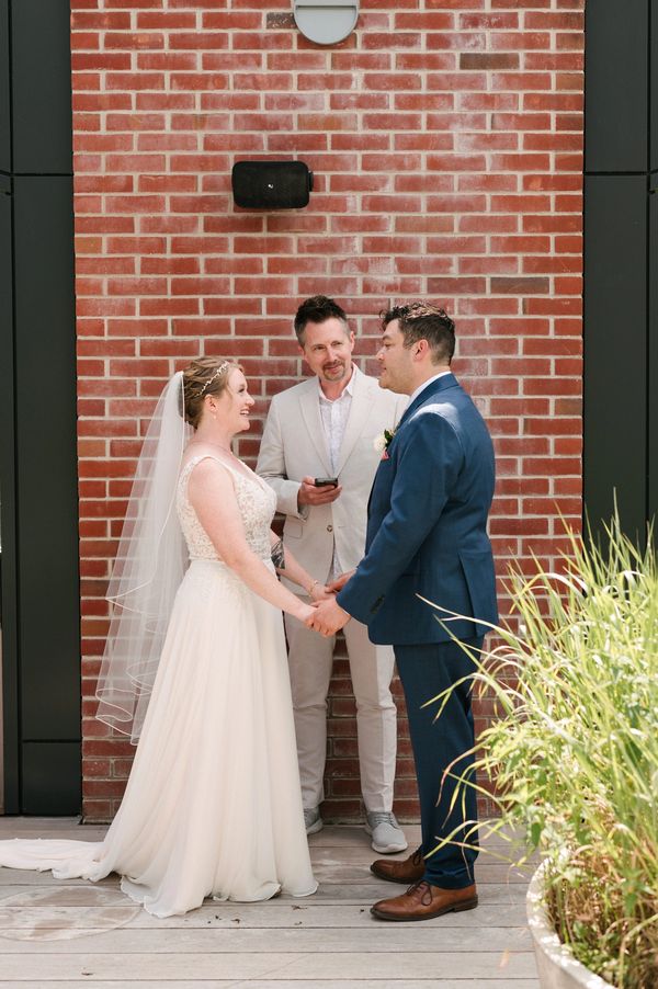 A simple ceremony on a roof top in front of a brick wall at the Royal Hotel.