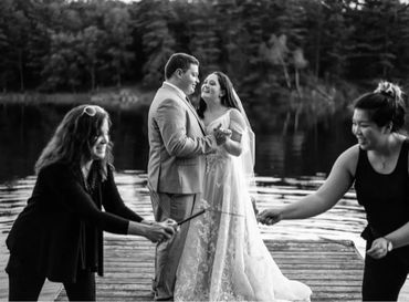 Two girls lighting fireworks while bride and groom dance in the background