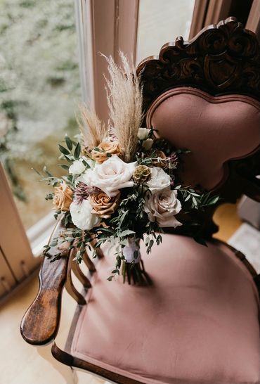 Bouquet sitting on a vintage chair covered in dusty rose fabric with a heart shaped back.