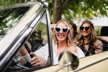 Bride and her bridesmaids going for a ride in a vintage Chevrolet.