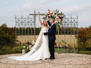 Bride and groom exctied to be married, standing in front of a decorative wrought iron fence.