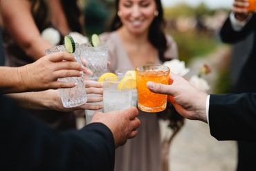 Wedding guests doing a cheers with a signature orange crush mocktail.
